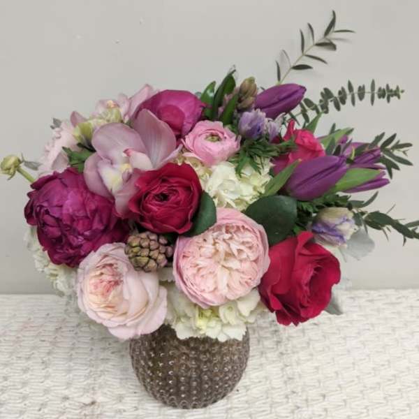Bouquet of pink, purple, and red flowers in a textured vase
