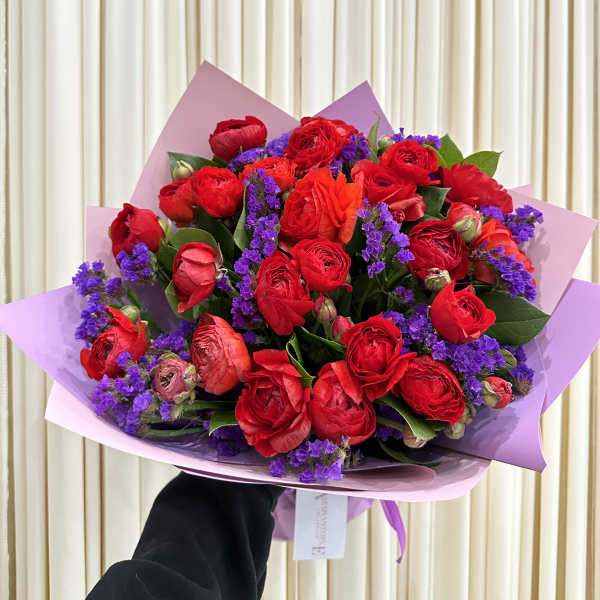 Bouquet of red roses with purple filler flowers in pink wrapping