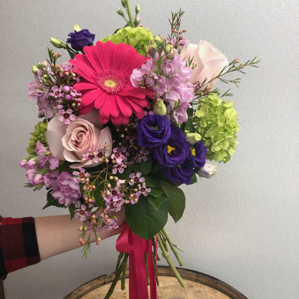 Hand-tied bouquet with pink gerbera, roses, and purple blooms