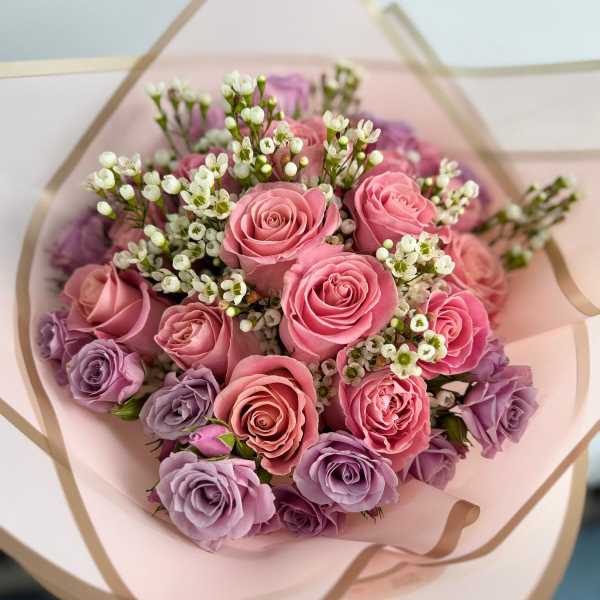 Bouquet of pink and lavender roses wrapped in pale pink paper