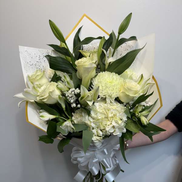 White bouquet with lilies, roses, and hydrangea wrapped in white paper
