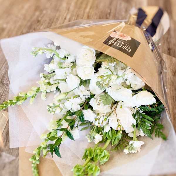 White flower bouquet wrapped in brown paper and clear plastic