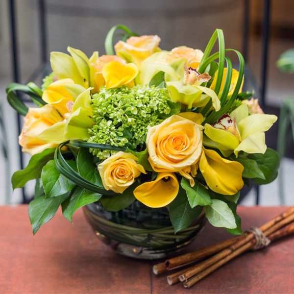 Yellow roses and calla lilies in a black vase with green accents