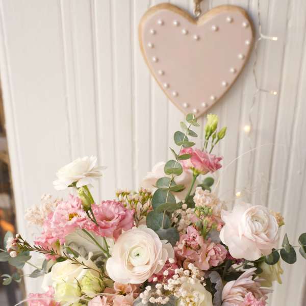 Pastel bouquet of pink and white flowers in a white container