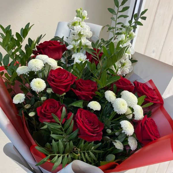 Bouquet of red roses and white flowers wrapped in red and gray paper