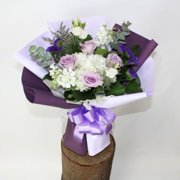 Bouquet of lavender and white flowers wrapped in purple paper