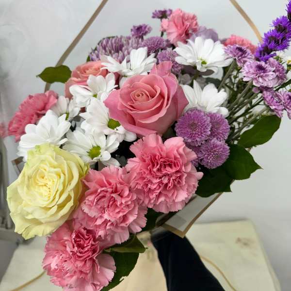 Bouquet of pink and white flowers with purple accents in clear wrap