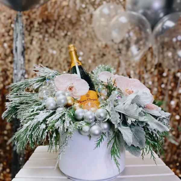 Champagne bottle in a white box with pink orchids and silver ornaments