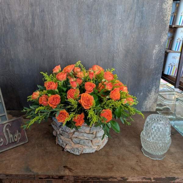 Orange rose bouquet in a stone-textured container
