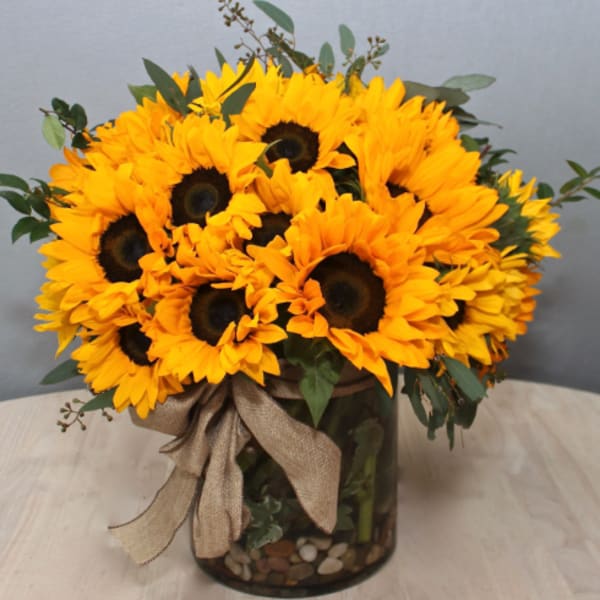 Bouquet of yellow sunflowers in a glass vase with a burlap ribbon