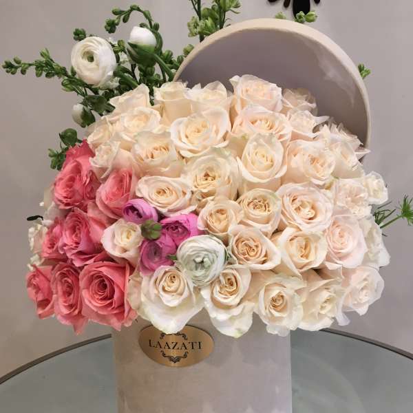 Bouquet of cream and pink roses in a round hatbox