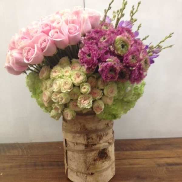 Pink and purple floral arrangement in a birch bark vase