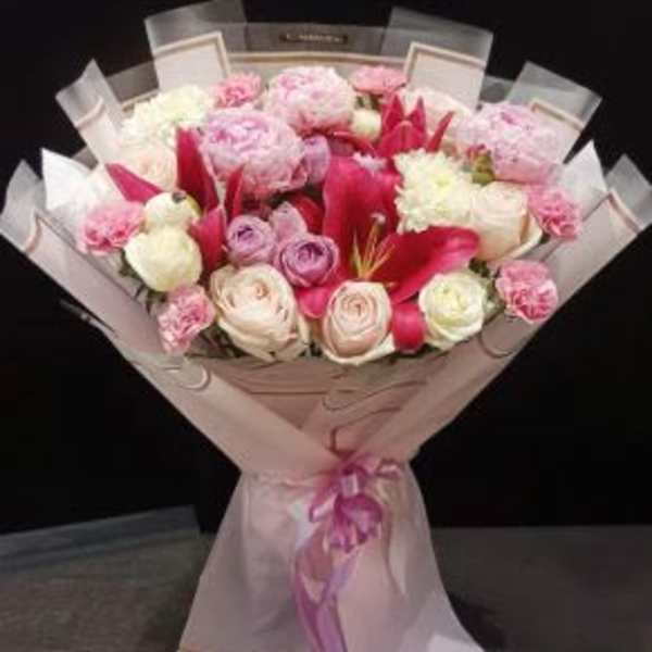 Pink and white bouquet with roses and lilies wrapped in pale paper