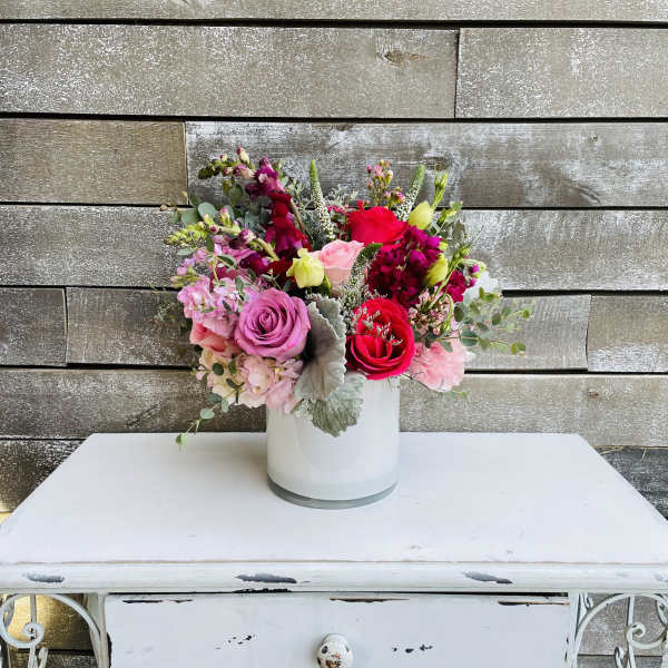 Mixed pink and red flower bouquet in a white vase