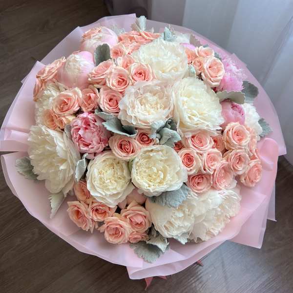 Bouquet of blush roses and white peonies wrapped in pink paper