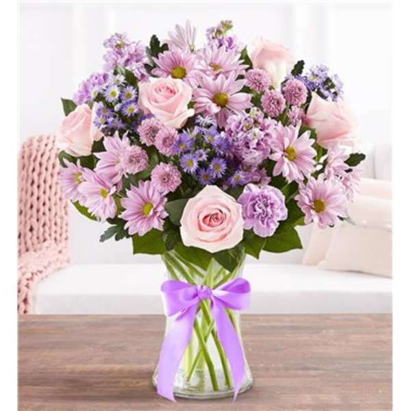 Pink and lavender bouquet in a glass vase with a purple ribbon