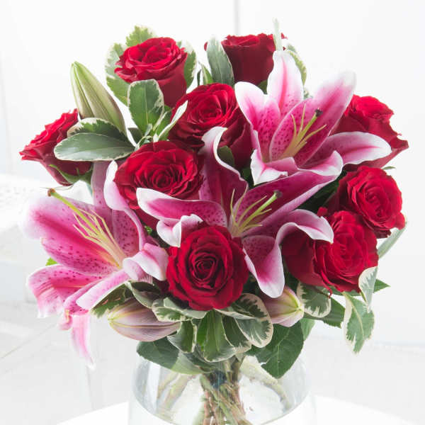Red roses and pink lilies in a clear glass vase