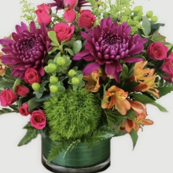 Bouquet of magenta chrysanthemums, pink roses, and orange alstroemeria in a green vase