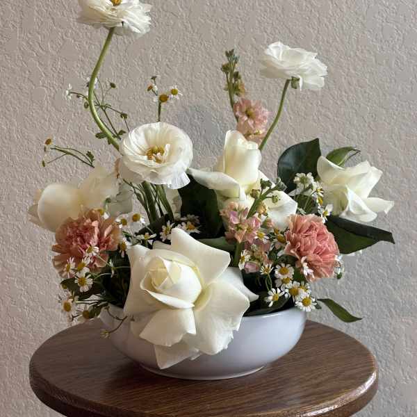 White roses and pink carnations in a white bowl vase