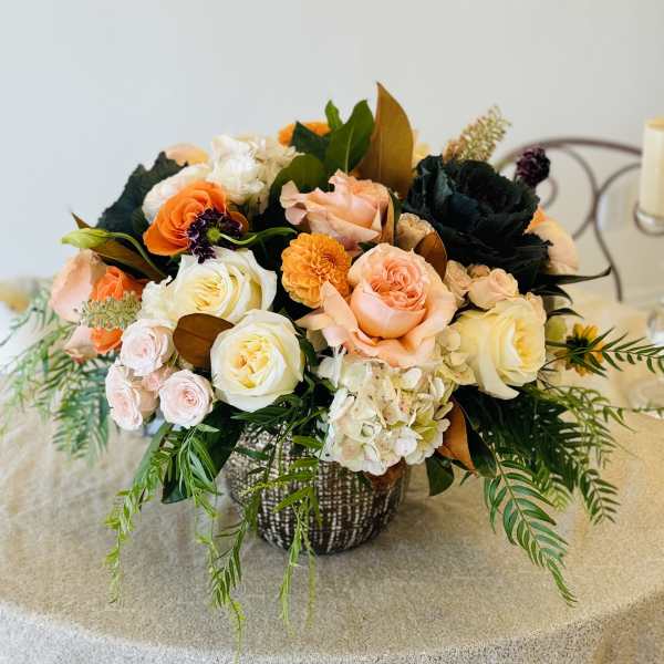 Mixed bouquet of peach, white, and orange roses in a woven basket