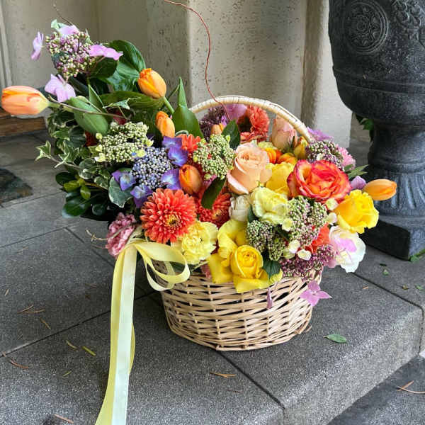 Basket of colorful mixed flowers with a ribbon bow