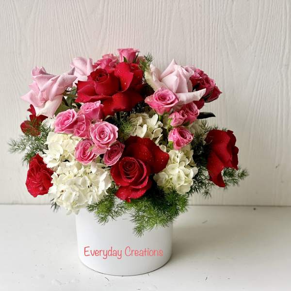 Pink and red roses arranged in a white container