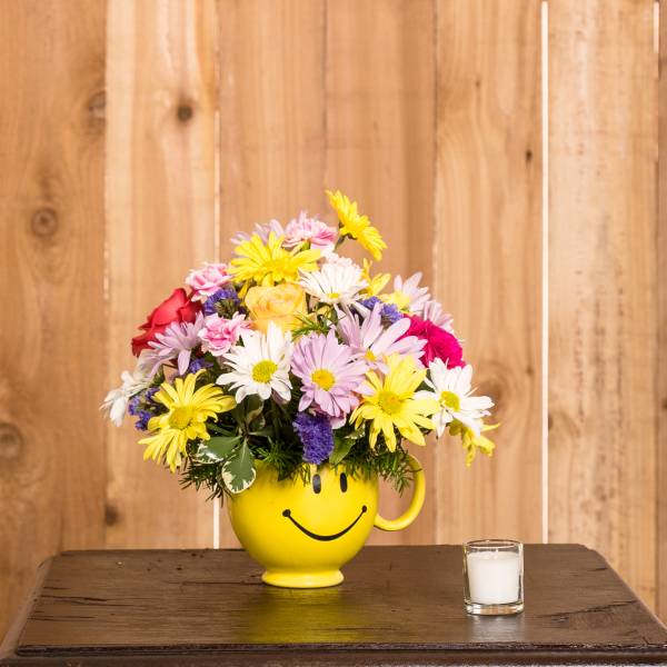 Colorful mixed bouquet in a yellow smiley-face mug vase