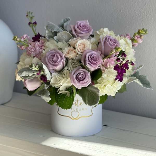 Lavender roses and white hydrangeas in a white hatbox