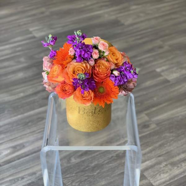 Bouquet of orange and purple flowers in a gold box