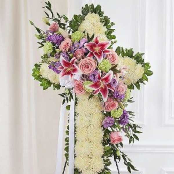 Standing floral cross with pink roses, lilies, and white blooms