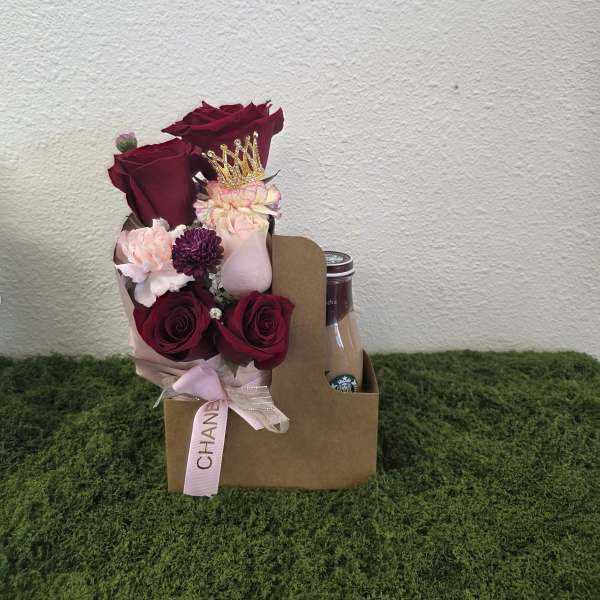 Bouquet of burgundy and pink roses in a gift box with a drink bottle