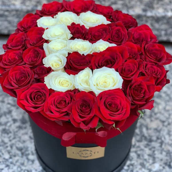 Red and white roses arranged in a round black box