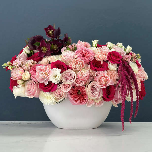 Pink and burgundy floral arrangement in a white vase