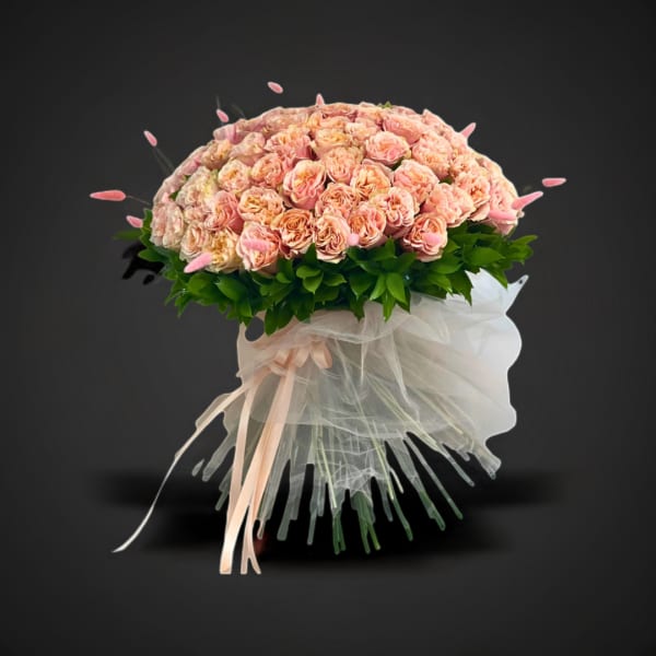 Large bouquet of peach-pink roses with white tulle wrapping and ribbon