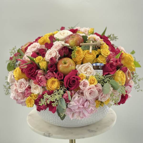 Mixed roses and apples arranged in a white bowl vase