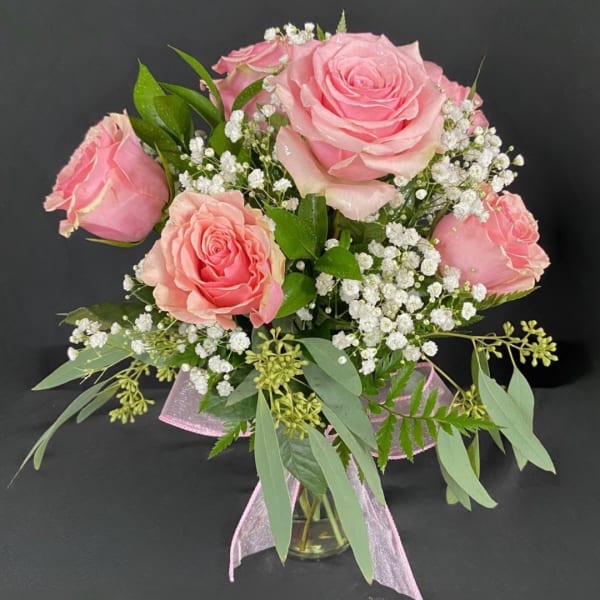 Pink roses with baby's breath in a glass vase tied with a pink ribbon