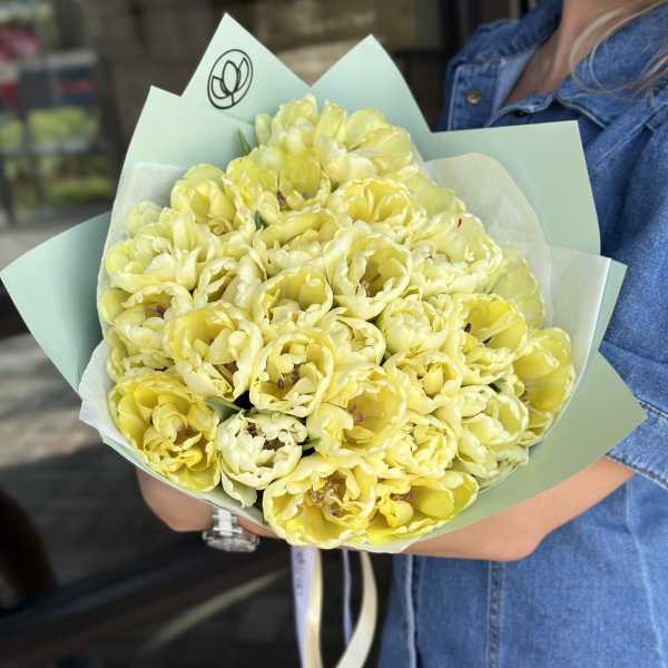 Bouquet of pale yellow tulips wrapped in mint paper