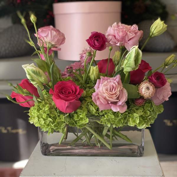Pink and magenta flower arrangement in a clear rectangular vase