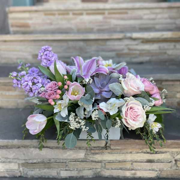 Pastel floral arrangement in a white container with pink roses and lilies