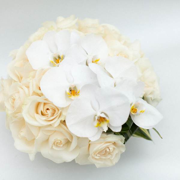 White orchids and cream roses in a compact bouquet