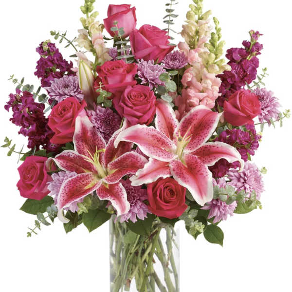 Pink roses and lilies arranged in a clear glass vase