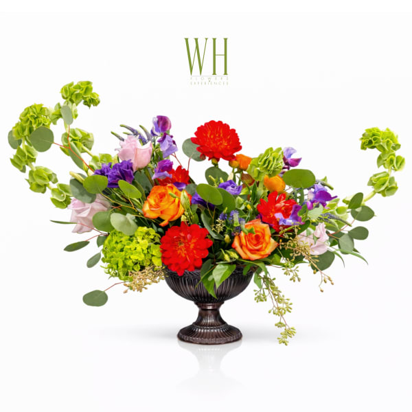 Colorful mixed flower arrangement in a dark urn vase