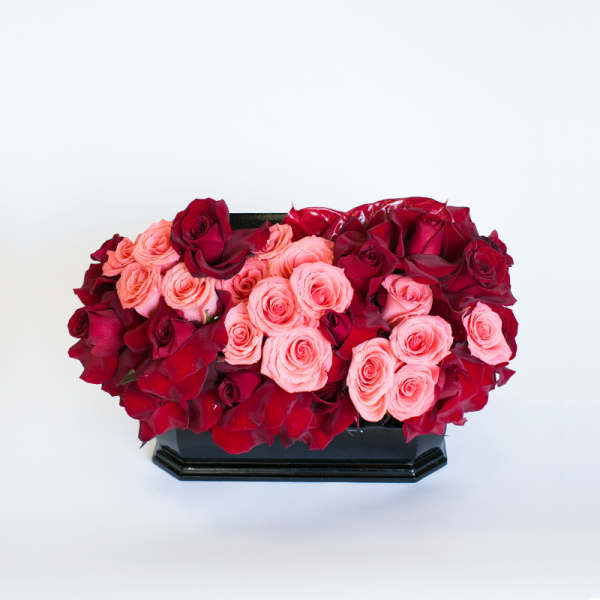 Red and pink roses arranged in a black rectangular vase