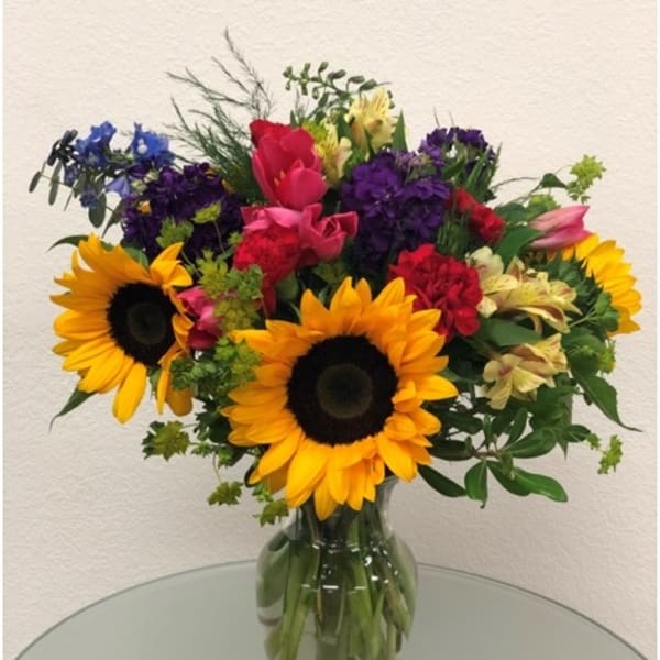 Colorful mixed bouquet with sunflowers in a glass vase