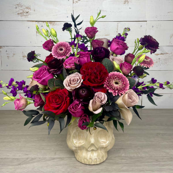 Mixed pink, red, and purple flowers in a skull-shaped vase