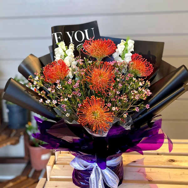 Bouquet of orange pincushion flowers with white blooms and purple wrapping