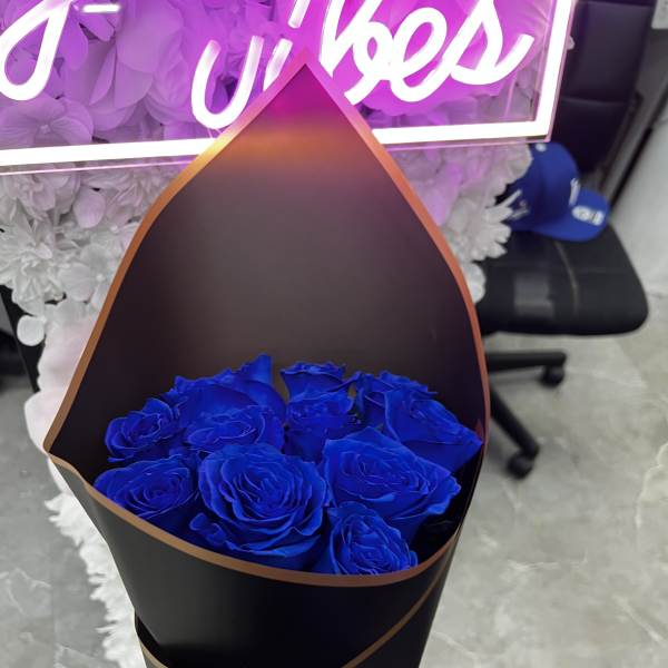 Bouquet of vivid blue roses wrapped in black paper with a blue ribbon