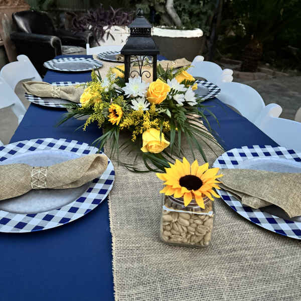 Yellow and white floral centerpiece with a lantern on a table