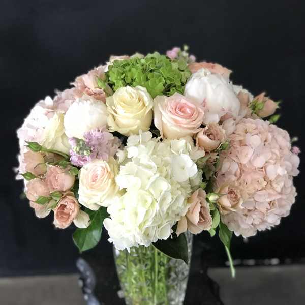 Pastel bouquet of roses and hydrangeas in a clear glass vase