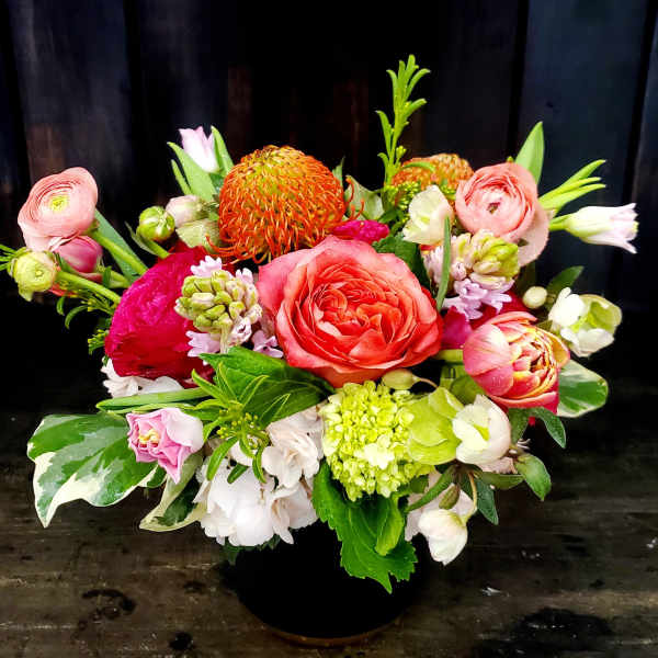 Mixed bouquet in a black vase with pink, orange, and white blooms